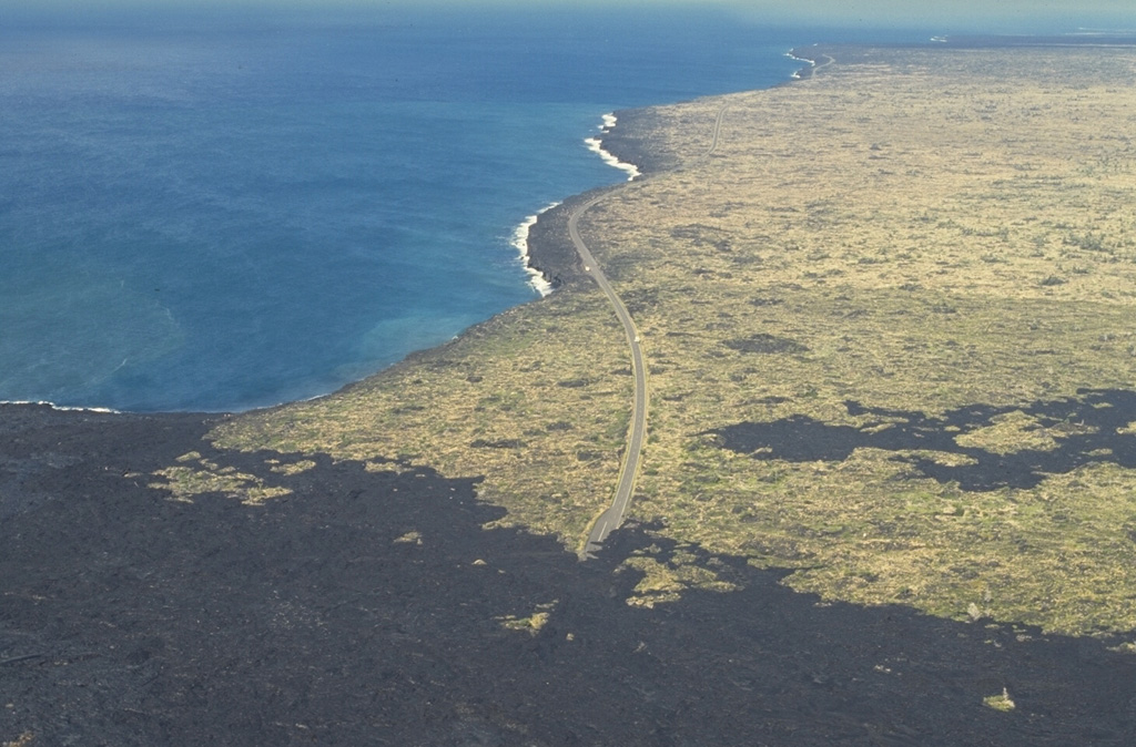The Laeapuki lava flow on Kilauea overran the coastal highway in April 1993, barely missing the Laeapuki ruins between the highway and the coast. After this June 1994 photo looking SW along the coast, lava flows overran the ruins. Lava flows from the East Rift Zone eruption that began in 1983 first reached the coast in 1986. By 1995 the flows had created 11 km of new coastline. Photo by Paul Kimberly, 1994 (Smithsonian Institution).