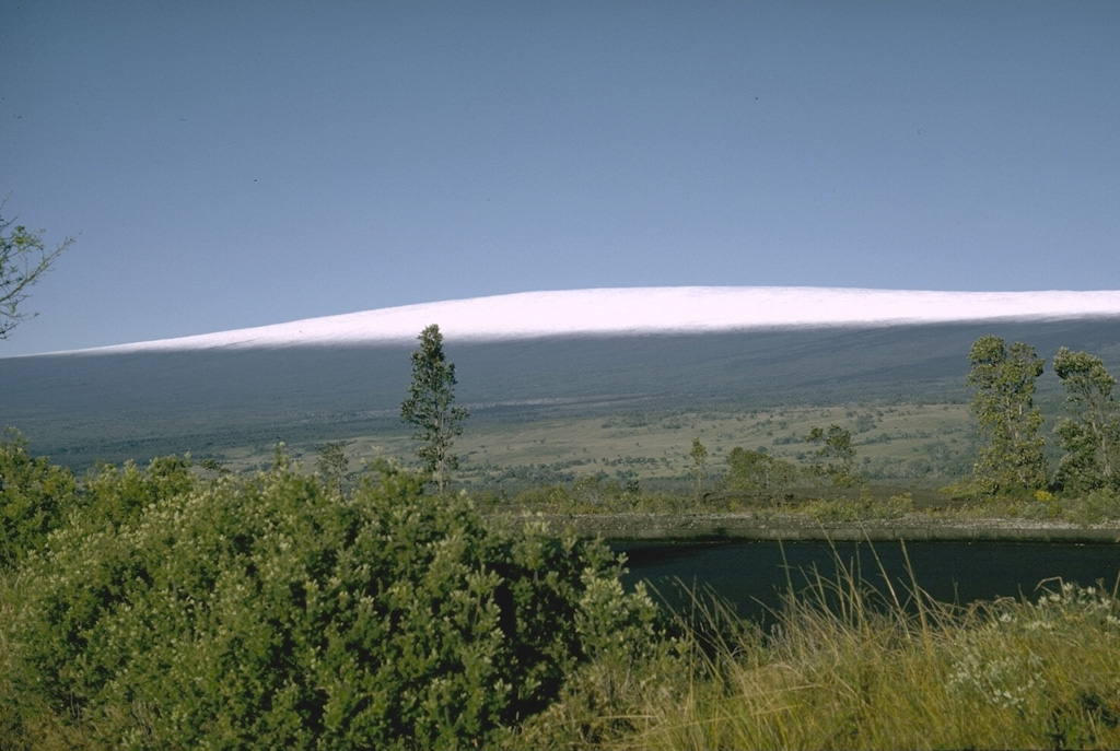 The low-angle flanks of Mauna Loa rise nearly 9 km from the sea floor. The elongated profile was created by repeated eruptions of thin lava flows, primarily from fissure vents along NE- and SW-trending rift zones. Almost 90% of the surface consists of lava flows less than 4,000 years old. Photo by Richard Fiske (Smithsonian Institution).