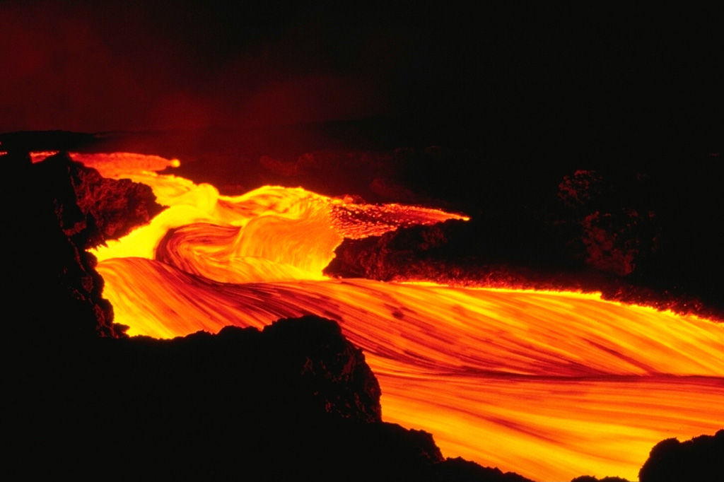 A stream of incandescent lava rapidly flows down the NE rift zone of Hawaii's Mauna Loa volcano during the early morning hours of an eruption that began on March 25, 1984.  The eruptive fissures, which initially opened within the summit caldera and on the SW rift zone, then rapidly migrated across the summit caldera.  Thereafter, activity was concentrated along the NE rift zone. Copyrighted photo by Katia and Maurice Krafft, 1984.