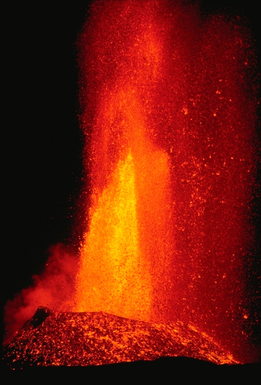 A lava fountain, fed by gas pressure within the basaltic magma of the 1984 Mauna Loa eruption, produces vertical jets of molten lava.  Still-fluid, incandescent lava bombs litter the slopes of a cone that was contructed by ejecta that accumulated around the vent.  This April photo was taken during a late stage of the eruption that began on March 25 and lasted until April 15. Copyrighted photo by Katia and Maurice Krafft, 1984.