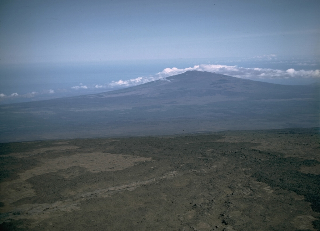 Hualalai shield volcano is seen here from the SE at the summit of Mauna Loa. Its latest eruption took place in 1800-01, when lava flows from vents on the NW rift zone reached the sea.  Photo by Lee Siebert, 1987 (Smithsonian Institution).