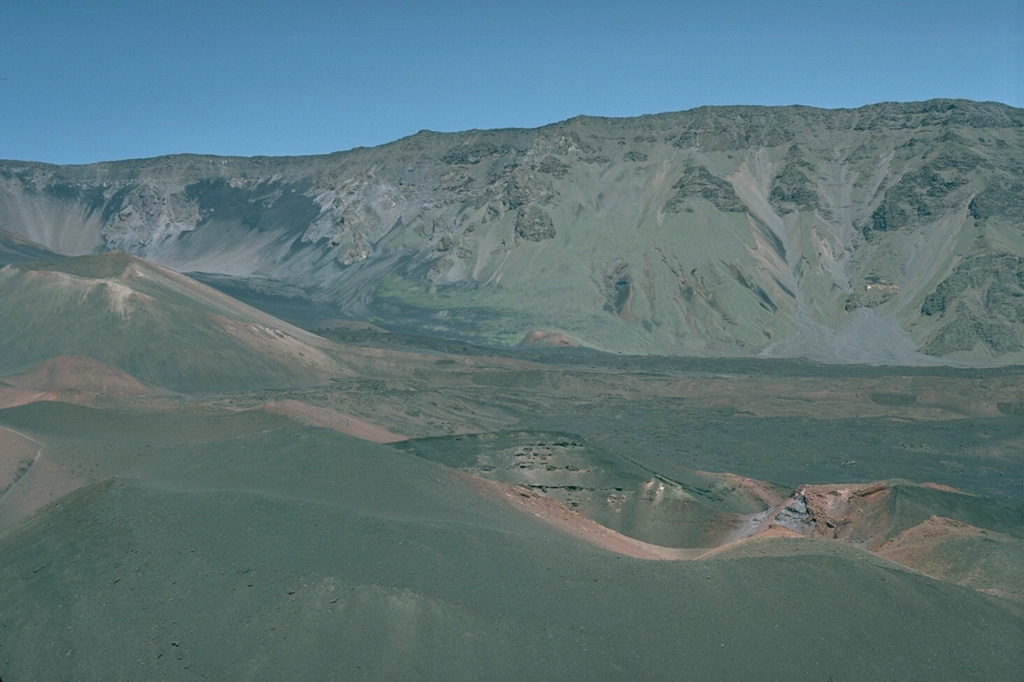 Halali'i (center foreground) and Pu’u o Maui (left center) are two of a series of young scoria cones erupted within the Haleakalā crater. Unvegetated lava flows form much of the crater floor, seen here looking NW from Pu’u Naue scoria cone. The crater is one of the few locations where the rare native-Hawaiian silversword ('ahinahina) plant is found.  Photo by Lee Siebert, 1987 (Smithsonian Institution).