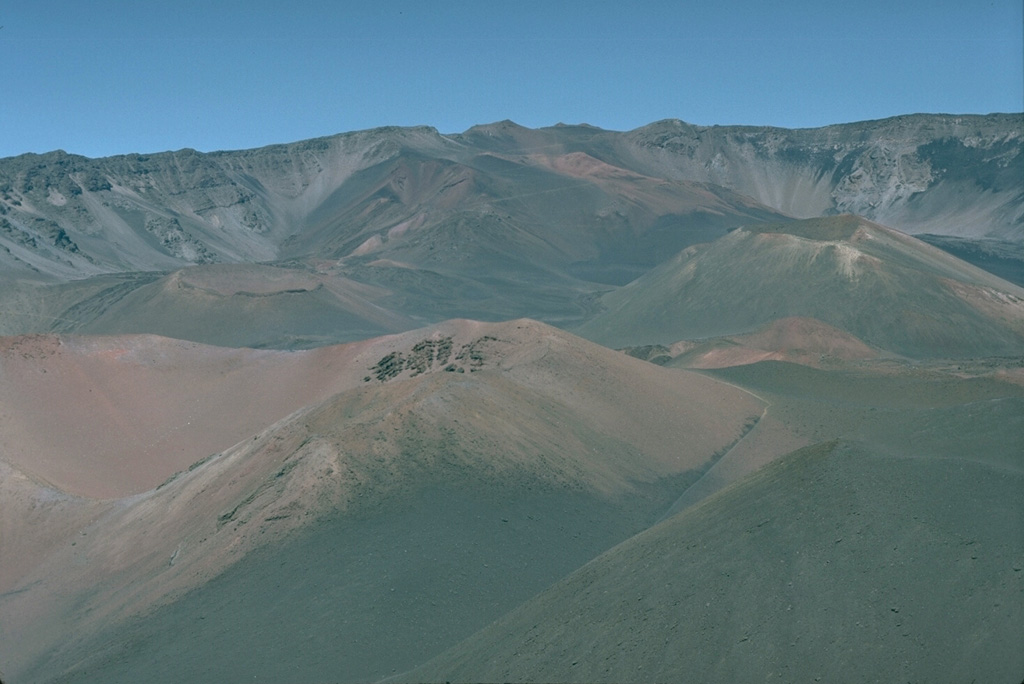 Kamoa o Pele (left) and Pu’u o Maui (right) are two of a group of young scoria cones along the southwest rift zone within the Haleakalā crater, seen here looking westward towards the Haleakalā summit. Photo by Lee Siebert, 1987 (Smithsonian Institution).