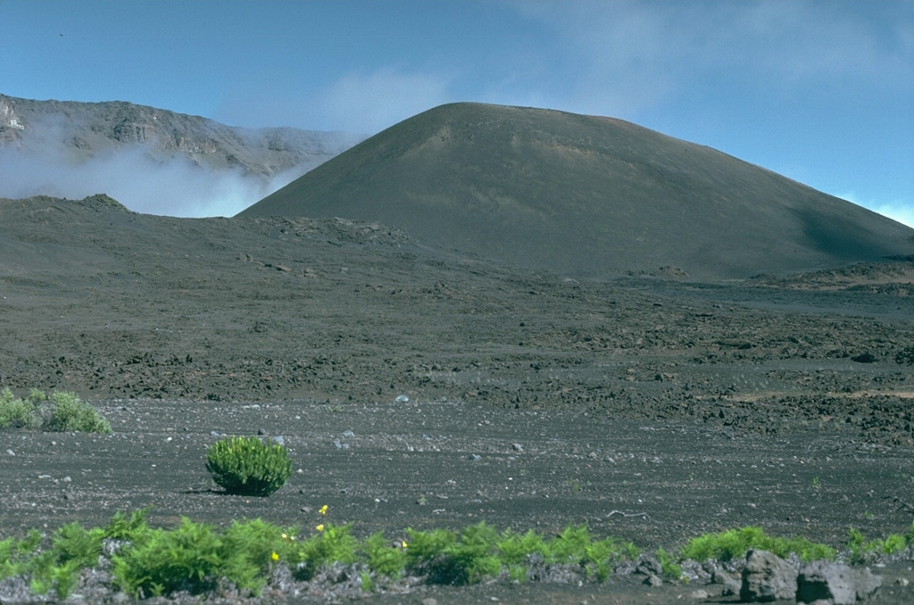 Pu’u o Maui is the largest of a group of scoria cones erupted along a rift zone that passes across Haleakalā crater, with the western crater rim to the upper left. The large summit crater formed through erosion and collapse events. Photo by Lee Siebert, 1987 (Smithsonian Institution).