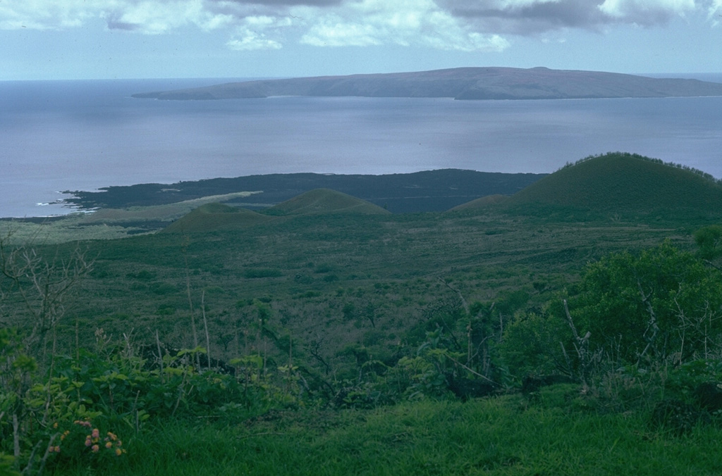 Recent activity at Haleakalā took place from vents low on the SW rift zone. The lava flows that form the coastline below originated from two vents, one near where this photo was taken and the other below the scoria cone near the center. Kaho’olawe is in the distance to the SW. Photo by Lee Siebert, 1987 (Smithsonian Institution).