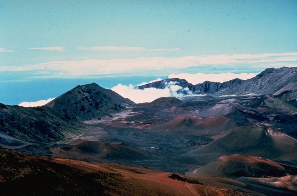 The summit of Haleakalā on the island of Maui contains a large crater that opens towards the ENE. It formed by the erosion of two large valleys that eventually coalesced, along with collapse events. This view to the NE from near the summit shows the Ko’olau Gap in the distance and scoria cones on the crater floor from eruptions along a major rift zone that extends across the summit from the SW to eastern coasts. Photo by Dick Stoiber, 1976 (Dartmouth College).