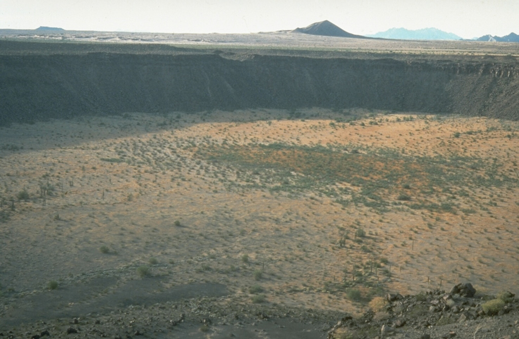 McDougal crater on the NW side of the Pinacate Volcanic Field in NW México is the largest maar at Pinacate. This view from the SE looks across the 1,520 x 1,740 m wide crater, which contains playa deposits 130 m below the rim. The maar erupted through flat-lying alluvial terrain of the Gran Desierto. Photo by Richard Waitt, 1988 (U.S. Geological Survey).