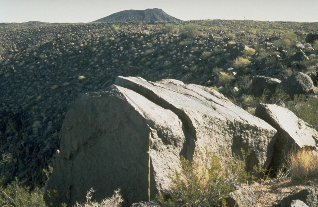 A large ejected block lies on the rim of Trebol maar in the NW part of the Pinacate volcanic field, immediately SE of Macdougal maar. The scale in front of the block has dark- and light-colored bars that mark 10 cm increments. The block fractured into three large segments following impact. Photo by Richard Waitt, 1988 (U.S. Geological Survey).