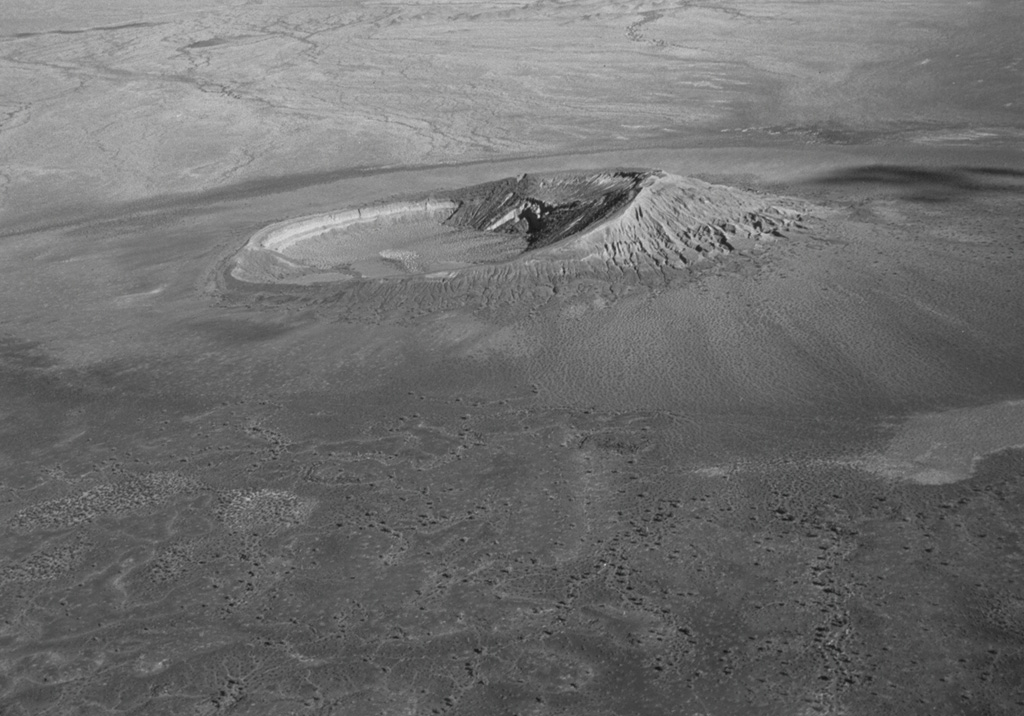 Cerro Colorado tuff cone is one of the most prominent features of the Pinacate volcanic field in Mexico. This aerial oblique view from the NW shows the 1-km-wide crater with the highest point on the S rim. Tuff beds that compose the S rim dip inward up to 20-25 degrees. Cerro Colorado's crater was formed during several episodes of phreatomagmatic eruptions from multiple vents, during which portions of the tuff cone slumped into the crater. Photo by David Roddy, 1965 (U.S. Geological Survey).