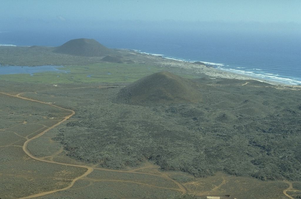The San Quintín Volcanic Field on the NW coast of Baja California contains lava flows and young scoria cones. This view looks south from Volcán Basu to Picacho Vizcaino (surrounded by young lava flows), and Volcán Sudoeste (upper left). These are among the youngest features of the San Quintín field.  Photo by Jim Luhr, 1990 (Smithsonian Institution).