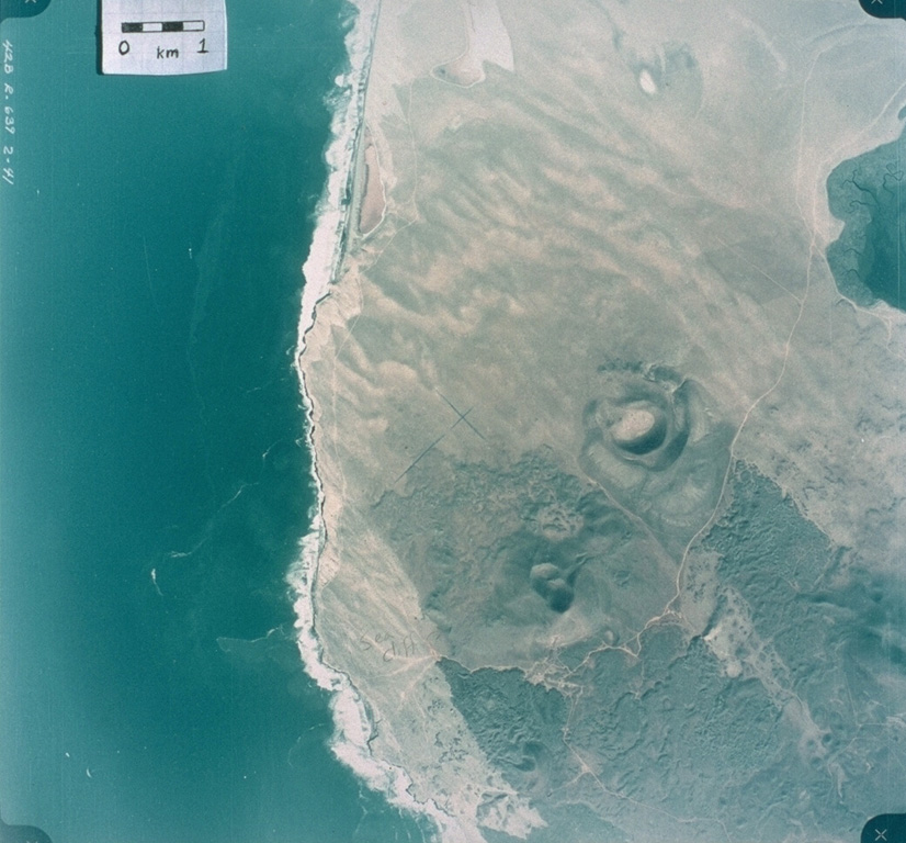 This 1978 aerial photo shows the nested craters of Volcán Riveroll (right-center) and the intersecting craters of Volcán Basu (below and to the left). The Riveroll craters open towards the NW (upper left). The darker basaltic lava flows extend to the SE from both cone complexes. The flow from Riveroll diverts around the Kenton scoria cone (edge of image at the lower right). The lighter areas are windblown sand. the Pacific coast shoreline is to the left, and the body of water to the upper right is part of San Quintín Bay. Aerial photo by Comisión de Estudios del Territorio Nacional (CETENAL), 1:25,000, 1978.