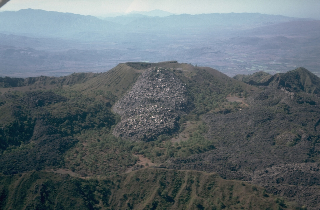This aerial view looks from the east across the inner summit caldera of Ceboruco. The unvegetated lava flow in the center was emplaced either in 1870-75, or during earlier eruptions in 1542 or 1567. The flow covering the caldera floor to the lower right is the near-vent portion of the voluminous El Norte lava flows. The ridge in the foreground is the eastern rim of the inner caldera. Photo by Jim Luhr, 1980 (Smithsonian Institution).