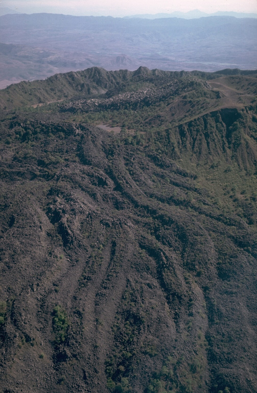 The El Norte lava flows cover most of the N flank of Ceboruco volcano in western México. The south wall of the inner caldera forms the far summit ridge. The andesitic El Norte flows cover a broad area 3.5 km in length and forms a 3.5-km-wide lava flow field at the base of the volcano. Their youthful morphology and unvegetated surfaces suggest a young age, possibly during one of the two 16th century eruptions. Photo by Jim Luhr, 1980 (Smithsonian Institution).