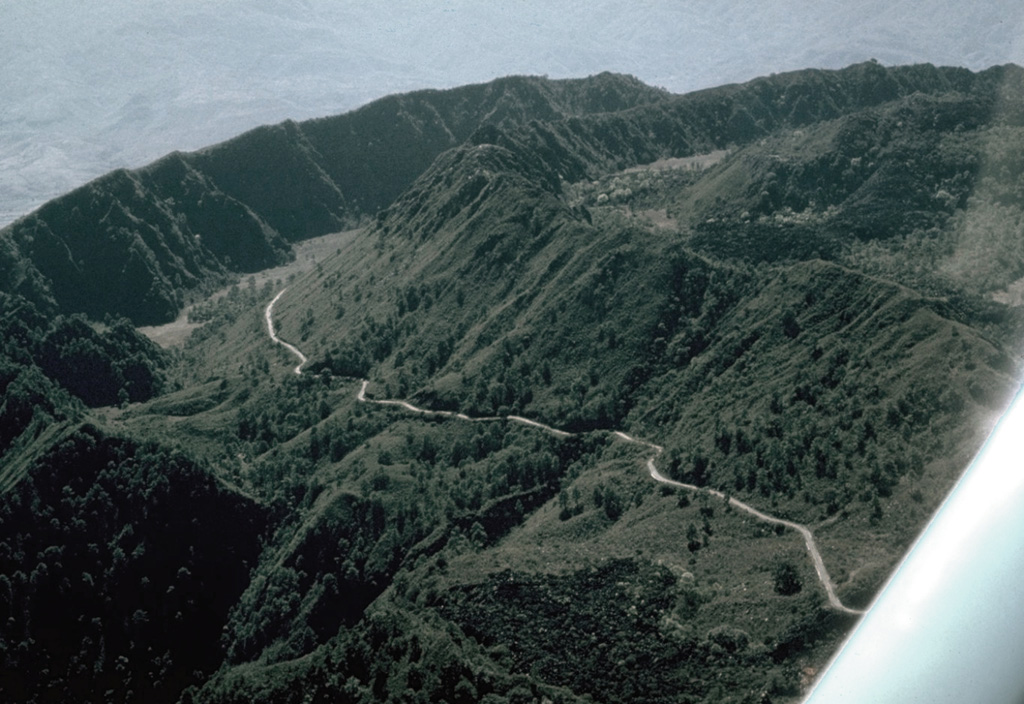 The walls of two nested summit calderas are seen here in an aerial view of Ceboruco from the NE, with the road to the summit. The formation of the 3.7-km-wide outer caldera was associated with eruption of the 5 km3 Jala Pumice and the Marquesado pyroclastic flow about 1,000 years ago. The Jala Pumice covers broad areas to the north and east. Photo by Jim Luhr, 1980 (Smithsonian Institution).