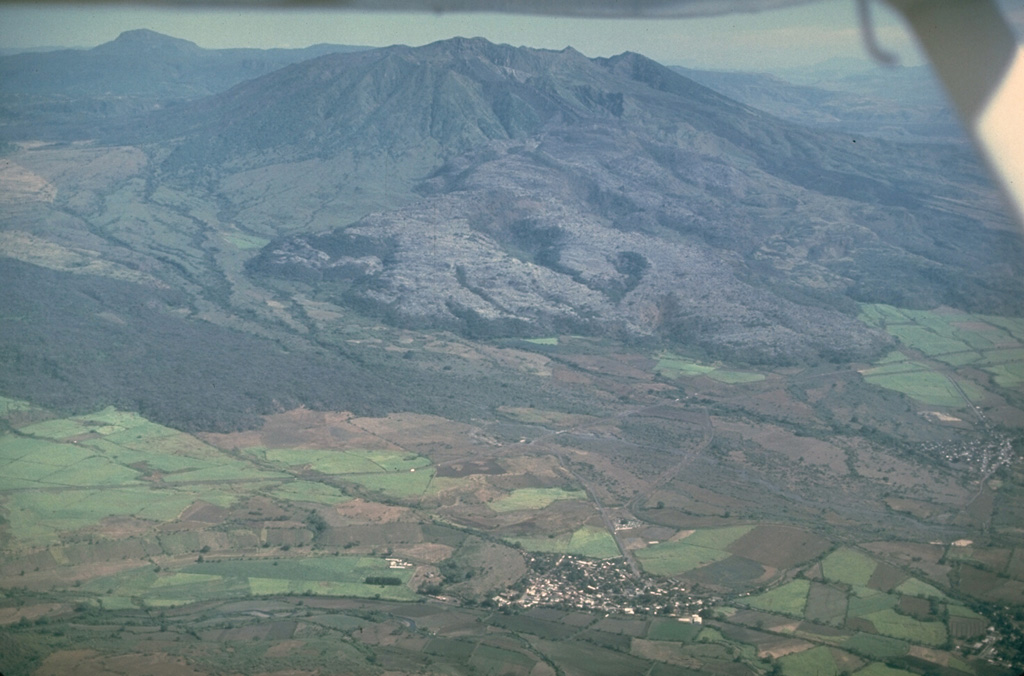 Volcán Ceboruco is a small, but complex stratovolcano with two concentric summit calderas. The thick lava flow (center) on the western flank was emplaced during an eruption in 1870-75. Eruption of the rhyodacite Jala Pumice formed the initial 4-km-wide caldera about 1,000 years ago. The second caldera was associated with partial collapse of the large Dos Equis dacite lava dome, which partly filled the earlier caldera. About 15 scoria cones and lava flows are across the flanks. Photo by Jim Luhr, 1980 (Smithsonian Institution).