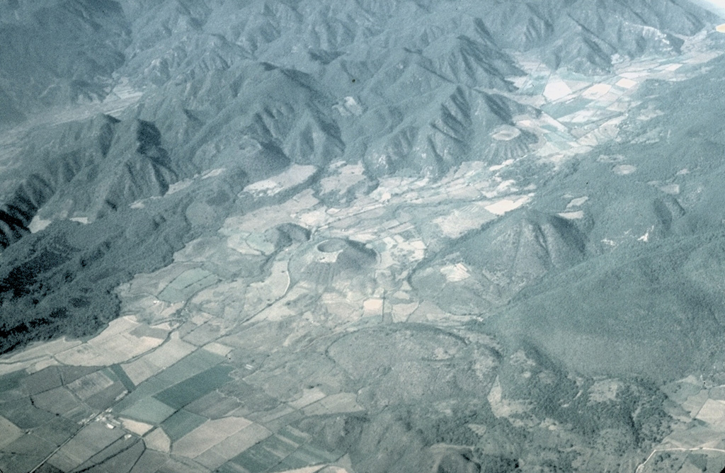 Part of the Mascota Volcanic Field in the Jalisco tectonic block east of Puerto Vallarta appears in this aerial view from the south. The scoria cone in the center is Volcán Molcajete, which along with the smaller Volcán Novillero to its left. The forested lava flow at the left side of the valley originated from Volcán Malpais. It is located at the valley margin above and left of Volcán Novillero. Photo by Steven Nelson, 1996 (Tulane University).