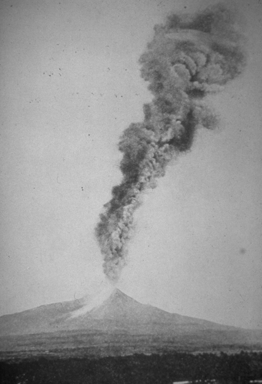 An ash plume towers above Colima on 7 March 1903 in this view from the south. A large explosive eruption on 15 February produced abundant ashfall and pyroclastic flows. The light-colored area down the flank to the left may be pyroclastic flow deposits. More than 20 large explosions, including this one, took place between 15 February and 14 March. Photo courtesy Julian Flores (University of Guadalajara), 1903.