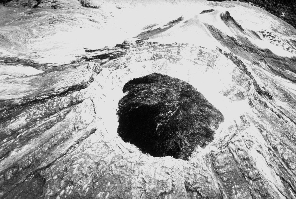 A 1941 aerial photo from the SW shows a dark lava dome that was extruded into the 450-m-wide crater created by the powerful explosive eruption of January 1913. In 1922 the crater floor had a depth of about 300 m and was covered by debris from the crater walls. By May 1930 the crater bottom lay about 150 below the crater rim, and when the crater was visited in January 1931 black lava was up to 50 m below the notch on the northern crater rim. Renewed dome growth in 1957 soon filled the crater and by 1961 lava began flowing over the crater rim. Photo courtesy Julian Flores (University of Guadalajara), 1941.
