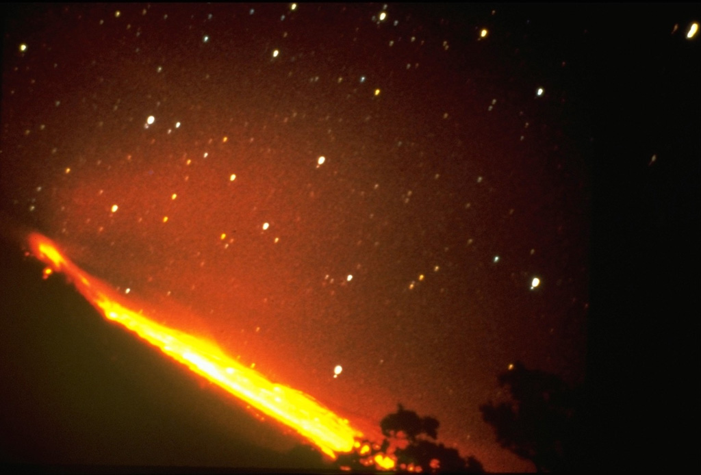 Incandescent blocks dislodging from a slow-moving lava flow create an incandescent path below stars in this 24 April 1961 night-time long exposure of Colima. Following lava dome growth in the summit crater, a lava flow began traveling down the northern flank in 1961 and reached the caldera moat by the end of 1962. Photo by José Suarez Jaramillo, 1961 (courtesy of Julian Flores, University of Guadalajara).