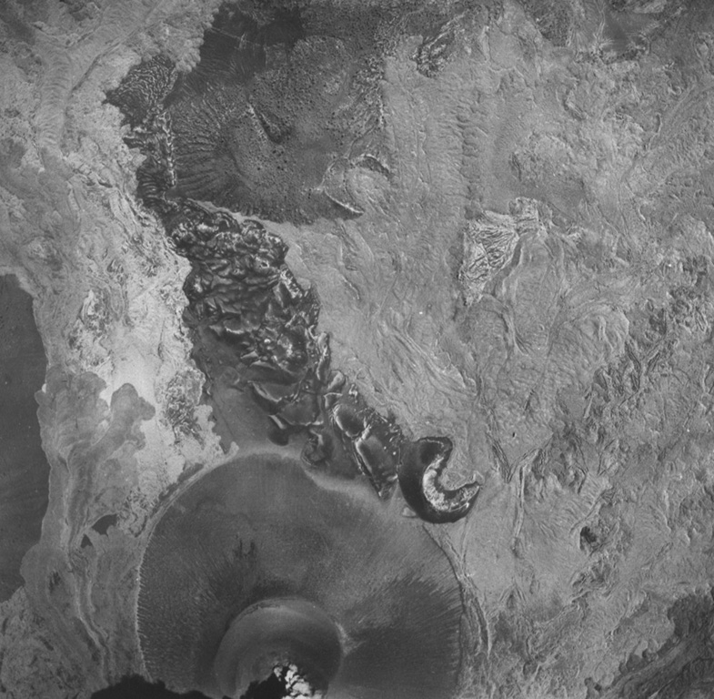 A vertical aerial photo of Parícutin taken on 26 May 1945 shows the cone at the bottom with the partially buried horseshoe-shaped Sapichu vent on its NE flank. Lava flows, forming the lighter-colored areas in the photo, surround the Quitzocho Ridge in the center of the photo and the older Cerro de Jarátiro scoria cone at the top. Ultimately nearly the entire Quitzocho Ridge was buried by lava flows.  Aerial photo by Comisión de Estudios del Territorio Nacional (CETENAL), 1:25,000, 1945.