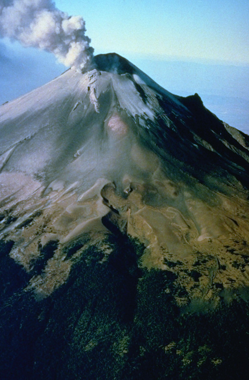 A plume rises above the eastern side of the summit crater of Popocatépetl in December 1994. Ash deposits from previous eruptions darken the glaciers on the upper flank. This aerial view from the NE shows the El Ventorillo peak on the right-hand horizon, the remnant of an older edifice. Photo courtesy CENAPRED, Mexico City, 1994.