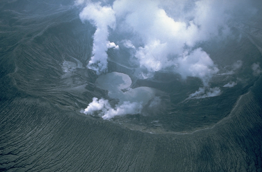 Gas-and-steam plumes emanate from the new El Chichón crater in June 1982, about two months after a major explosive eruption formed it. The first sighting into the crater revealed three small lakes on the crater floor. These later merged into a single lake that reached a maximum depth of about 120 m. This aerial view from the east also shows gully erosion within pyroclastic flow and surge deposits on the flanks.  Photo by Wendell Duffield, 1982 (U.S. Geological Survey).