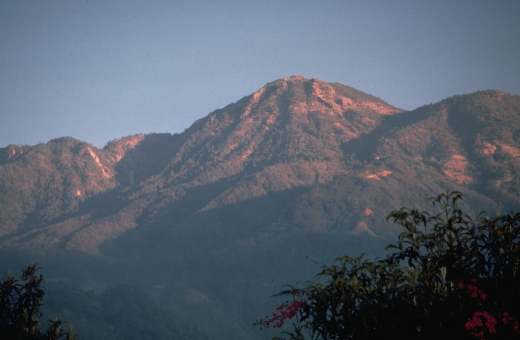 Tacaná lies about 30 km south of the Polochic‐Motagua fault, in the zone which marks the Caribbean and North American plate boundary. The summit, seen here from the SSE, is elongated as a result of the extrusion of a series of lava domes with the youngest center, San Antonio, being at the SW (left). In the center is the Tacaná itself, with Chichuj to the right. Photo by Norm Banks, 1987 (U.S. Geological Survey).