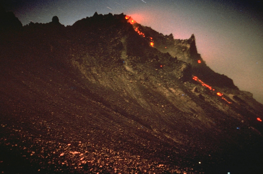 Incandescence is visible at the top of the growing Santiaguito lava dome in Guatemala. Rockfalls of hot material produce a visible trail down its northern flank. The dome began growing in 1922 in a large crater formed on the SW flank of Santa María volcano during a powerful explosive eruption in 1902. Dome growth has been continuous since 1922 and has produced a composite dome over 3 km long. This photo of El Brujo, the westernmost vent, was taken on 12 November 1967. Photo by Charles Pineo, 1967 (Dartmouth College, courtesy of Dick Stoiber).