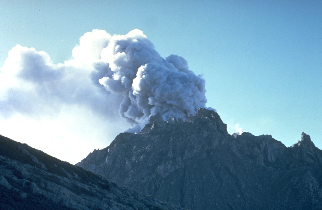 An ash plume rises above the Caliente vent in February 1968. Lava spines protrude from the easternmost vent of the Santiaguito lava dome. The flank of the Santa María edifice appears to the left in this view from the north. Photo by Dick Stoiber, 1968 (Dartmouth College).