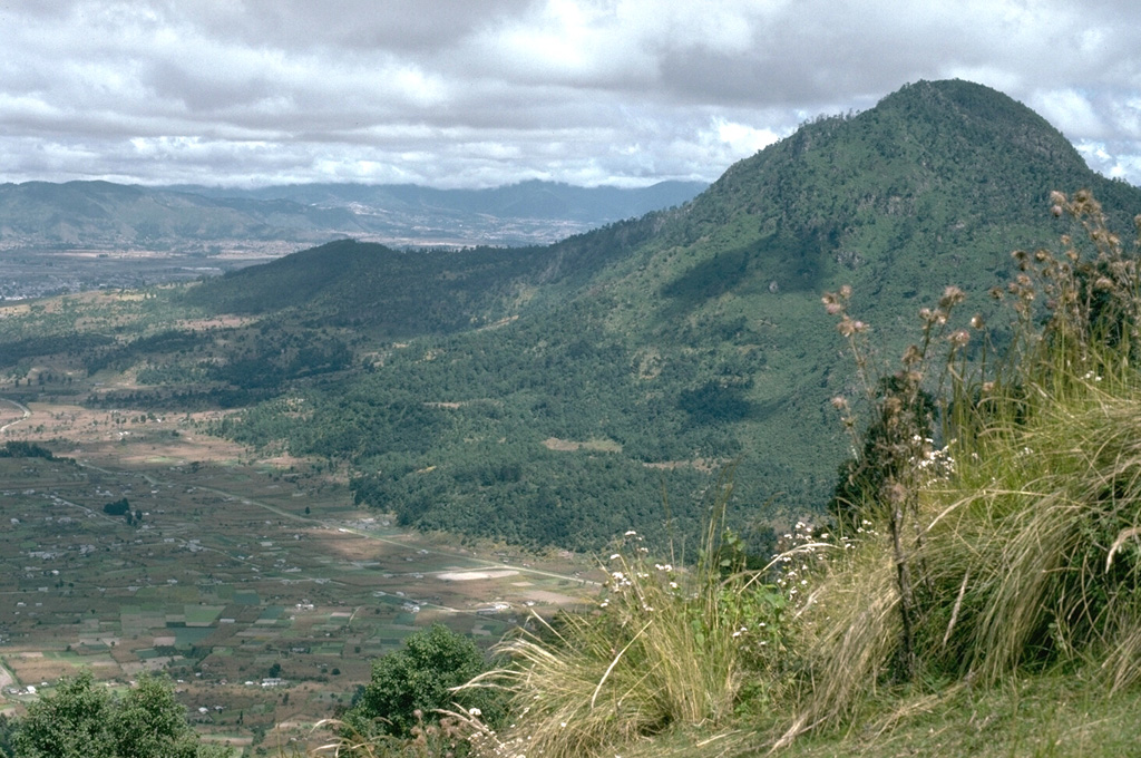 Cerro Quemado, seen here from the SW, is the youngest lava dome complex of Volcán de Almolonga. It is located immediately south of Guatemala's second largest city, Quezaltenango, the outskirts of which are visible to the upper left. The dome complex consists of a series of domes and flows. Photo by Lee Siebert, 1993 (Smithsonian Institution).