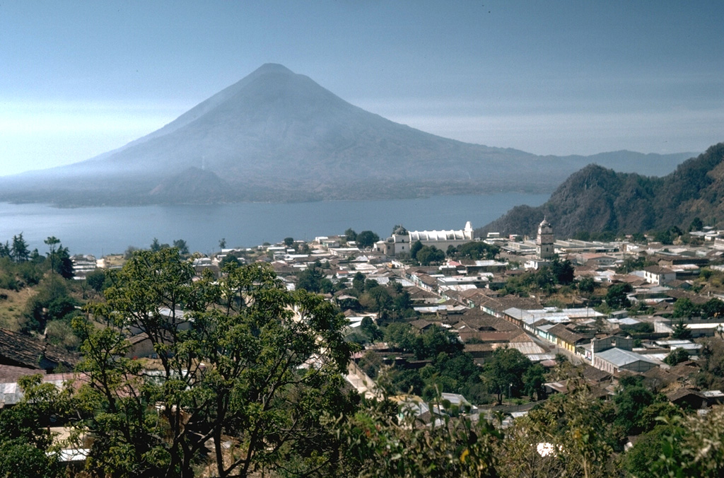 Atitlán and Tolimán volcanoes rise above Lake Atitlán in this view from the town of Sololá north of the lake. Atitlán is the taller of the two and forms the skyline immediately behind and to the left of Tolimán. The Cerro de flank lava dome immediately above the lakeshore to the lower left of the summit erupted within the past few thousand years. The two volcanoes were constructed over the buried rims of two Miocene-Pleistocene Atitlán calderas. Photo by Lee Siebert, 1988 (Smithsonian Institution).