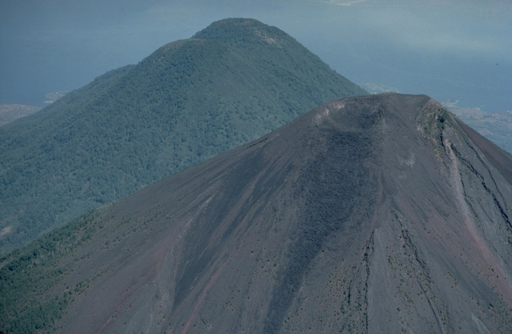 Atitlán (foreground) and Tolimán are twin volcanoes located immediately south of Lake Atitlán (background).  Tolimán was constructed on the buried rim of the Atitlán II caldera, whereas Volcán Atitlán was built 4 km south over the rim of the Atitlán III caldera.  Atitlán, whose summit area remains unvegetated, has been active in historical time.  Tolimán has not had historical eruptions, but has erupted within the past 1000 years. Copyrighted photo by Katia and Maurice Krafft, 1983.