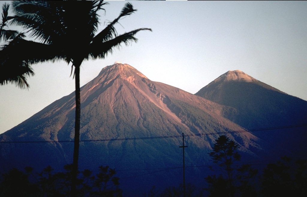 The upper SE flanks of Fuego (left) and Acatenango (right) are seen here, with their summits that lie only 3 km apart along a N-S line. The modern Fuego edifice was constructed within a scarp left by collapse of the ancestral Mesata, whose flank appears to the right of the summit towards the saddle between the two.  Photo by Lee Siebert, 1988 (Smithsonian Institution).