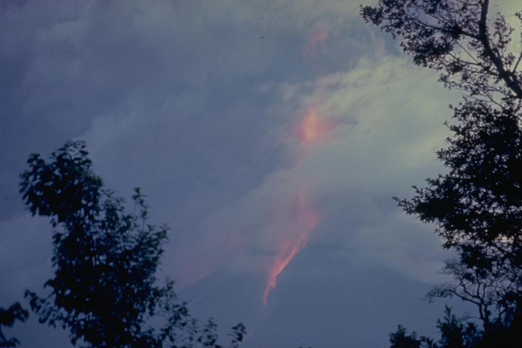 An ash plume with incandescent ejecta rises high above the summit of Fuego and produces hot avalanches down its flanks during this 12-13 August 1966 eruption. Ash fills much of the sky in this view. The ash plume rose to 12 km during this large but brief eruption. Photo by Dick Stoiber, 1966 (Dartmouth College).