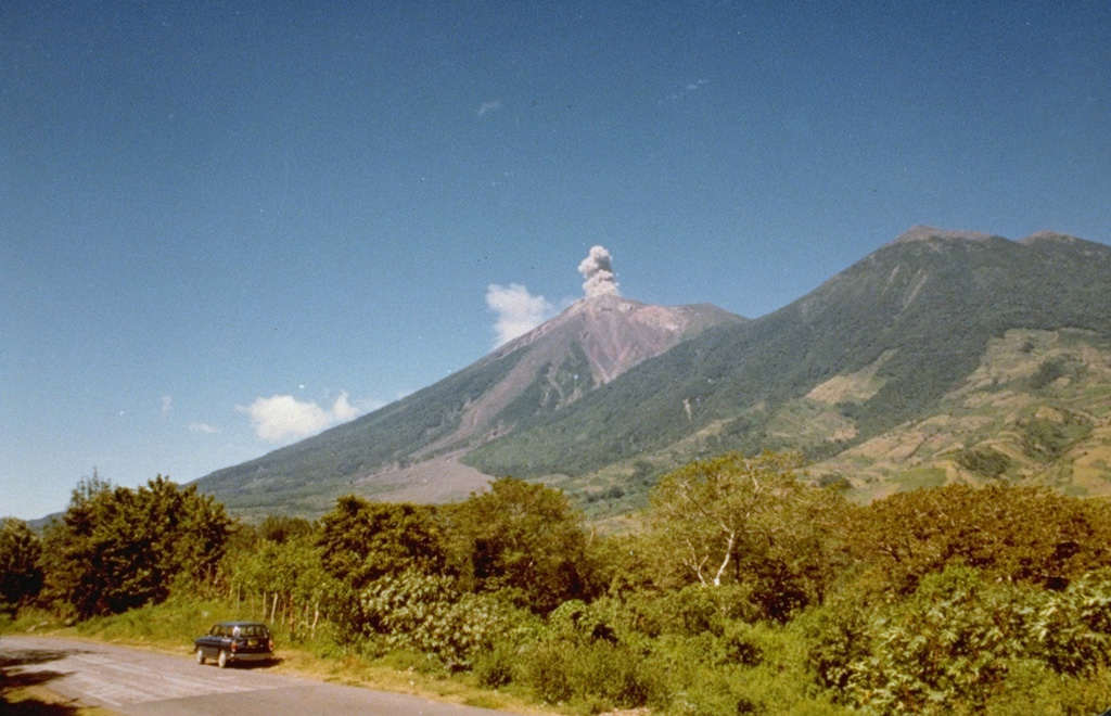A small ash plume rises at Fuego on 10 October 1977, seen here from the NE along the road to Alotenango, about 10 km away. Intermittent minor ash took place from 11 September 1977 to 8 August 1979, sometimes accompanied by pyroclastic flows and lava flows. Explosions were often closely spaced.  Photo by Paulino Alquijay, 1977 (courtesy of Pete Newton).