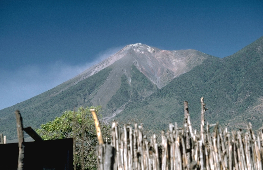 The summit of Fuego was constructed within a massive collapse scarp in the older Meseta edifice, remnants of which form the flat ridge to the right. This collapse may have happened about 8,500 years ago. The forested lower slopes of Acatenango can be seen at the right in this view from the NE. Photo by Lee Siebert, 1988 (Smithsonian Institution).