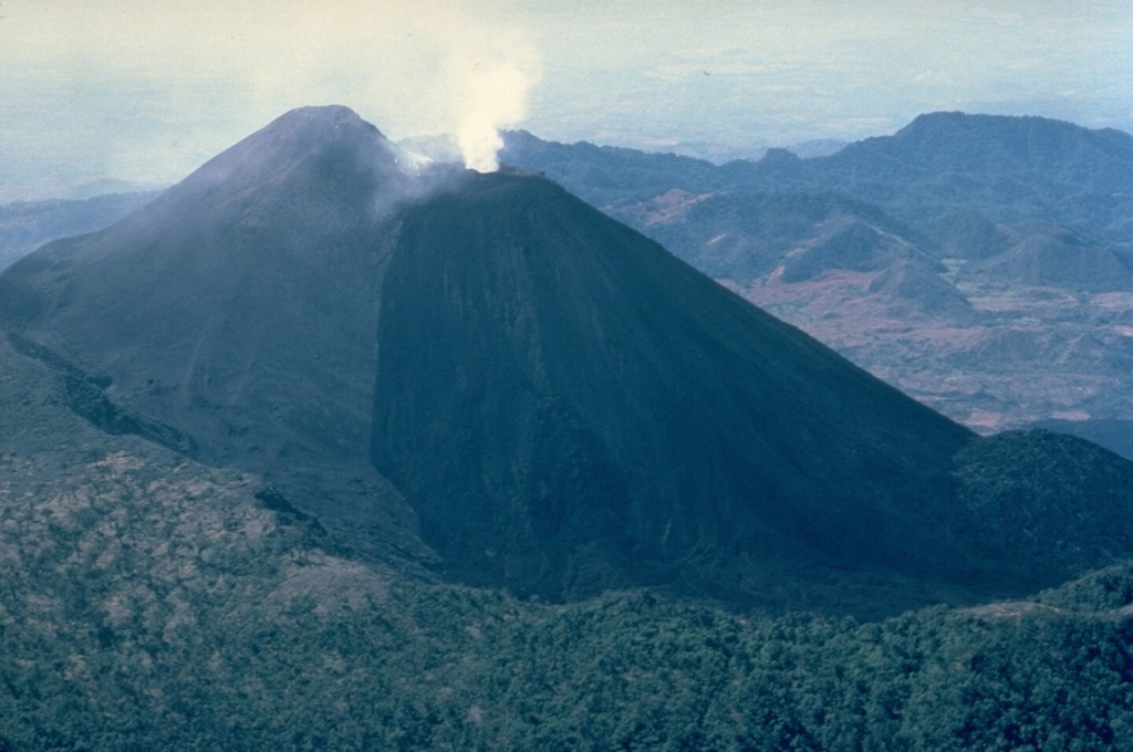 Eruptions from Pacaya, one of Guatemala's most active volcanoes, are frequently visible from Guatemala City, the nation's capital.   The modern Pacaya volcano (MacKenney cone) has grown within an arcuate caldera rim (visible at the lower part of this 1983 photo from the NE) that was created by a massive landslide.  During the past several decades, activity at Pacaya has consisted of frequent strombolian eruptions with intermittent lava flow extrusion on the flanks of McKenney cone, punctuated by occasional larger explosive eruptions.   Copyrighted photo by Katia and Maurice Krafft, 1983.