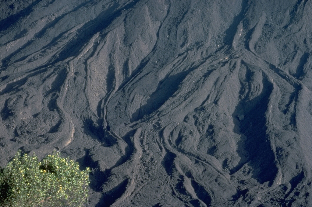 Fresh lava flows drape the slopes of MacKenney cone on Guatemala's Pacaya volcano.  This March 1983 photo from Pacaya's caldera rim shows many individual flow lobes whose margins are outlined by prominent levees.  A long-term eruption of Pacaya began in 1965.  Frequent strombolian eruptions were often visible from Guatemala City, and lava flows such as these armored the slopes of the summit cone.   Copyrighted photo by Katia and Maurice Krafft, 1983.