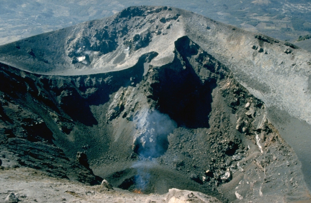 A small spatter cone ejects incandescent lava bombs at the bottom of MacKenney crater in early February 1990. Activity had resumed at Pacaya in early January after a long quiescence following a major explosive eruption 7-10 March 1989. This eruption removed the upper 75 m of MacKenney cone and enlarged the 50 x 75 m crater to the 200 x 350 m seen here. Photo by Alfredo MacKenney, 1990.