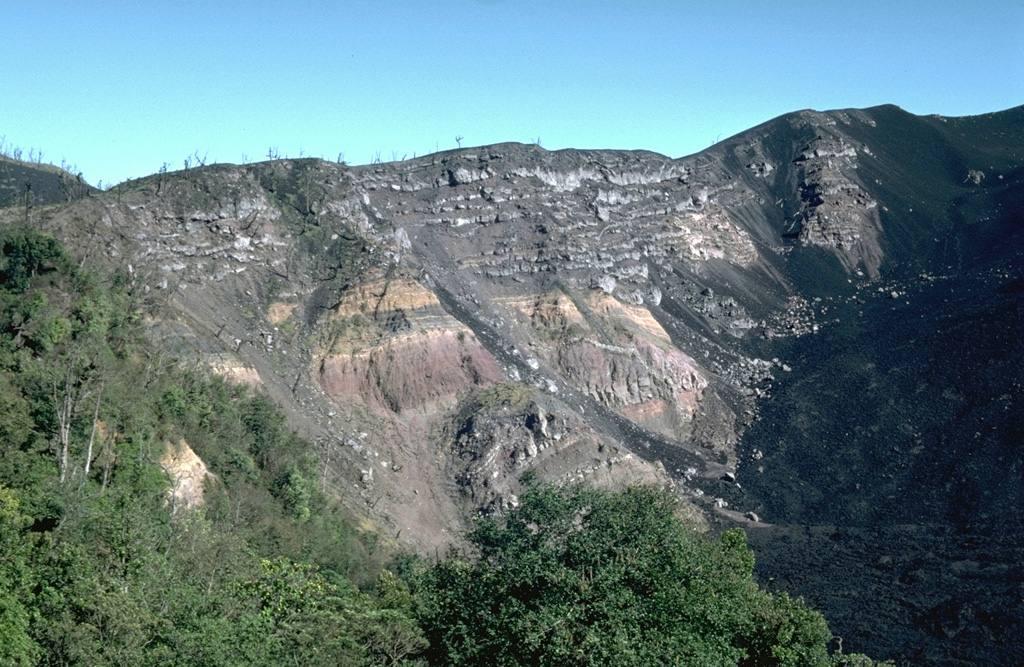 Large-scale collapse of the Pacaya summit sometime between about 1,550 and 600 years ago created a large horseshoe-shaped scarp. Collapse was followed by a large explosive eruption that produced widespread pyroclastic surges. This roughly 150-m-high section of the NW scarp exposes light-colored lava flows overlying pyroclastic deposits of the pre-collapse edifice. Subsequent eruptions have constructed a new cone within the caldera. Lava flows from MacKenney cone (out of view to the right) are slowly filling in the caldera moat. Photo by Lee Siebert, 1988 (Smithsonian Institution).