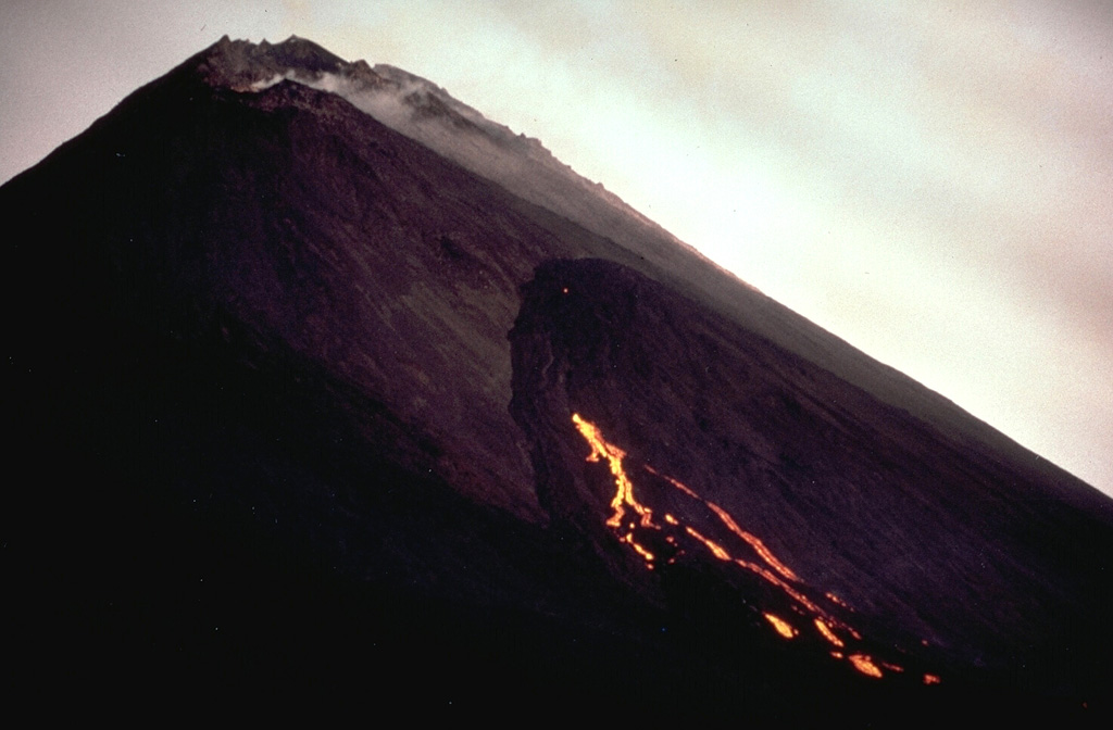 A lava flow extrudes from a WNW-flank vent on MacKenney cone at Pacaya on 10 January 1987. A weak gas plume can be seen from the summit crater, which was producing Strombolian eruptions at the same time.  Photo by Klaus Mehl, 1987 (GEOMAR, Germany).