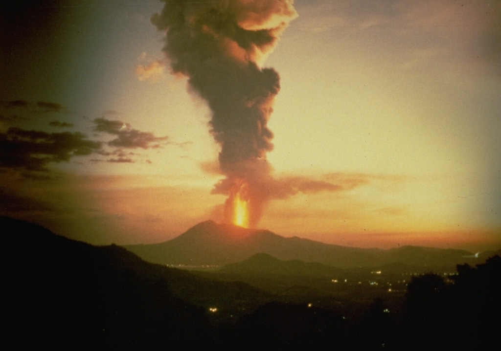 A lava fountain and ash plume rises above Pacaya, seen here in 1987 from the NW along the highway to Antigua Guatemala. Strombolian eruptions began in 1965 and were periodically interrupted by larger explosions such as this one, which deposited ash across wide areas. Anonymous photo courtesy Norm Banks (U.S. Geological Survey), 1987.