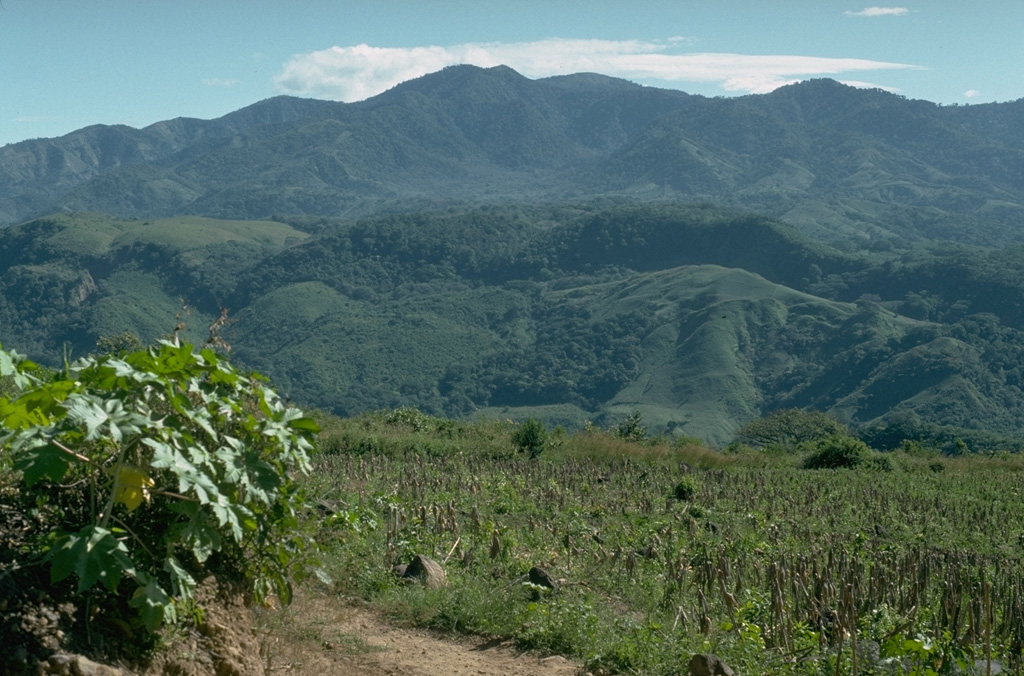 The western side of the low-angle, eroded Ixhuatán volcanic complex rises beyond the Río Los Esclavos as seen from the flank of Tecuamburro volcano.  The 1718-m-high dominantly andesitic volcano is of Pliocene-Pleistocene age.  The youngest center is a dacitic lava-dome complex at Cerro los Achiotes.  The domes and associated ashfall and ashflow deposits partially fill and extend from a horseshoe-shaped caldera that is breached to the SE and may have formed as a result of slope failure.         Photo by Lee Siebert, 1988 (Smithsonian Institution).