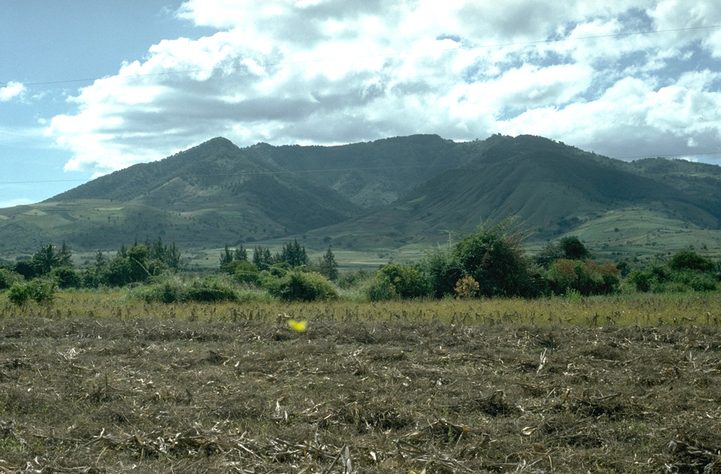 Volcán Tahual rises about 700 m above plains south of the town of Monjas, seen here from the NE. The summit contains a broad erosional depression that opens at the NE base of the volcano (center). A Holocene cone near the NE base of Volcán Tahual produced a short lava flow, now vegetated to the right. Photo by Lee Siebert, 1993 (Smithsonian Institution).