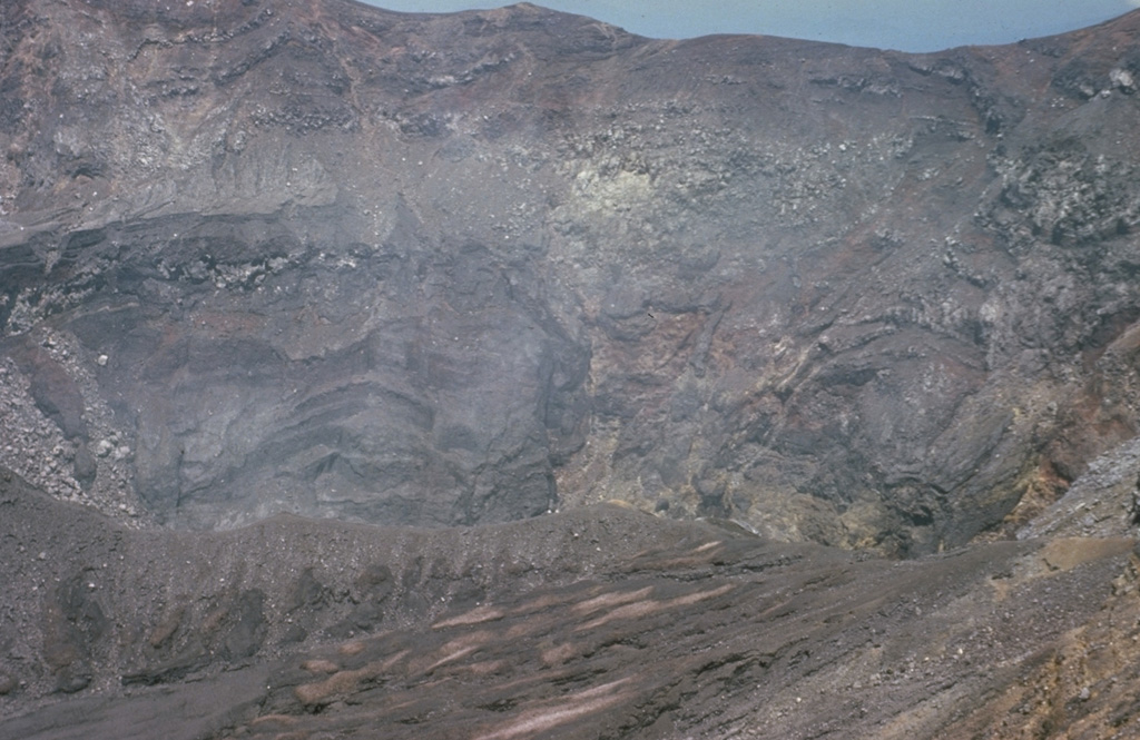 The active Santa Ana crater lies at the SE end of series of four nested summit craters and contains a small lake not visible in this photo. The northern crater wall in the background exposes a series of lava flows and inter-bedded pyroclastic deposits. Several faults are visible in the crater walls, such as the one at the upper left. Later tectonic movements produced a graben in the central part of the crater with displacements of 50-70 m.  Photo by Bill Rose, 1966 (Michigan Technological University).