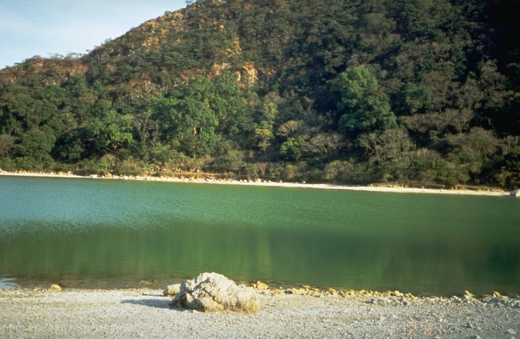 The Tecapa volcano summit contains the 600-m-wide Laguna de Alegría crater lake, seen here from the west. The 0.9 x 1.3 km crater is elongated in an E-W direction and lies about 300 m below the summit.  Photo by Kristal Dorion, 1994 (U.S. Geological Survey).