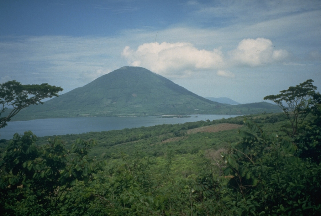 Isla el Tigre is a small, 5-km-wide island across a narrow strait south of Isla Zacate Grande in the Gulf of Fonseca of Honduras.  The conical, 783-m-high stratovolcano, seen here from the NE on Zacate Grande island, is less dissected than Zacate Grande volcano and is of probable Holocene age.  A single satellitic cone (far right) overlooks the NW-flank town of Amapala, Honduras' only Pacific port.  The peak in the distance beyond the right-hand flank is the volcanic island of Meangura. Photo by Mike Carr, 1991 (Rutgers University).