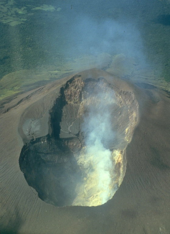 This photo taken on July 1987 looks into the double summit crater of Telica volcano in Nicaragua. An older shallower crater is located on the SW side (top). A plume rises from fumaroles in the 120-m-deep NE crater (bottom), which is the source of recent eruptions.  Photo by William Melson, 1987 (Smithsonian Institution).