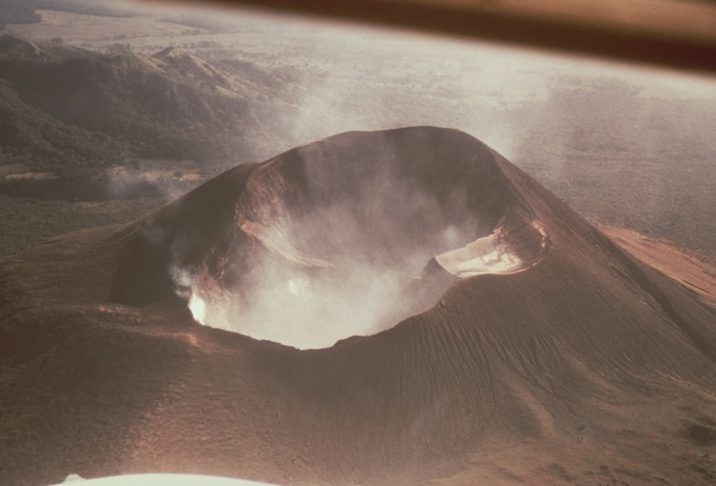 Steam fills the large double crater of Telica volcano in this 1968 aerial view from the NE.  The crater is about 300 x 700 m wide; its morphology suggests several generations of crater formation.  Most recent eruptions have occurred from the lower NE crater. Photo by William Melson, 1968 (Smithsonian Institution).