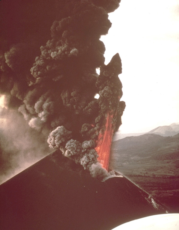 An incandescent lava fountain and a thick ash-laden eruption column rise above the summit crater of Cerro Negro volcano in 1968.  Ash columns were distributed primarily to the west, and intense ashfall affected the León-Chinandega area, one of the most densely populated and important agricultural areas in Nicaragua.  This aerial view from the SE shows the Telica and San Cristóbal volcanic complexes in the far right distance.   Photo by William Melson, 1968 (Smithsonian Institution).